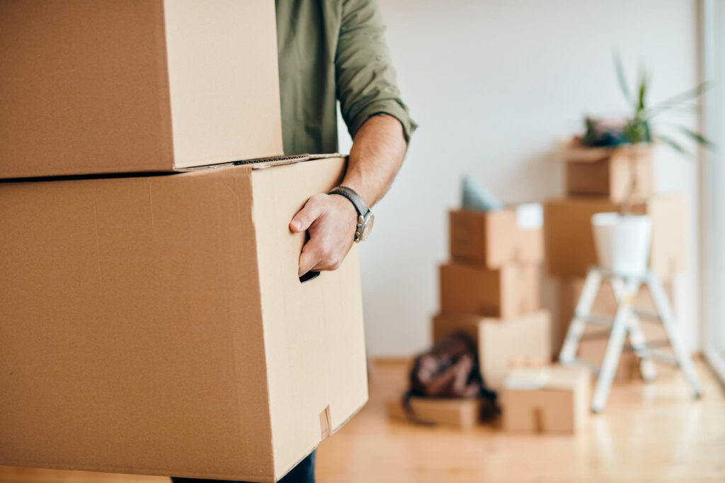 closeup-man-carrying-cardboard-boxes-while-relocating-into-new-apartment closeup-man-carrying-cardboard-boxes-while-relocating-into-new-apartment
